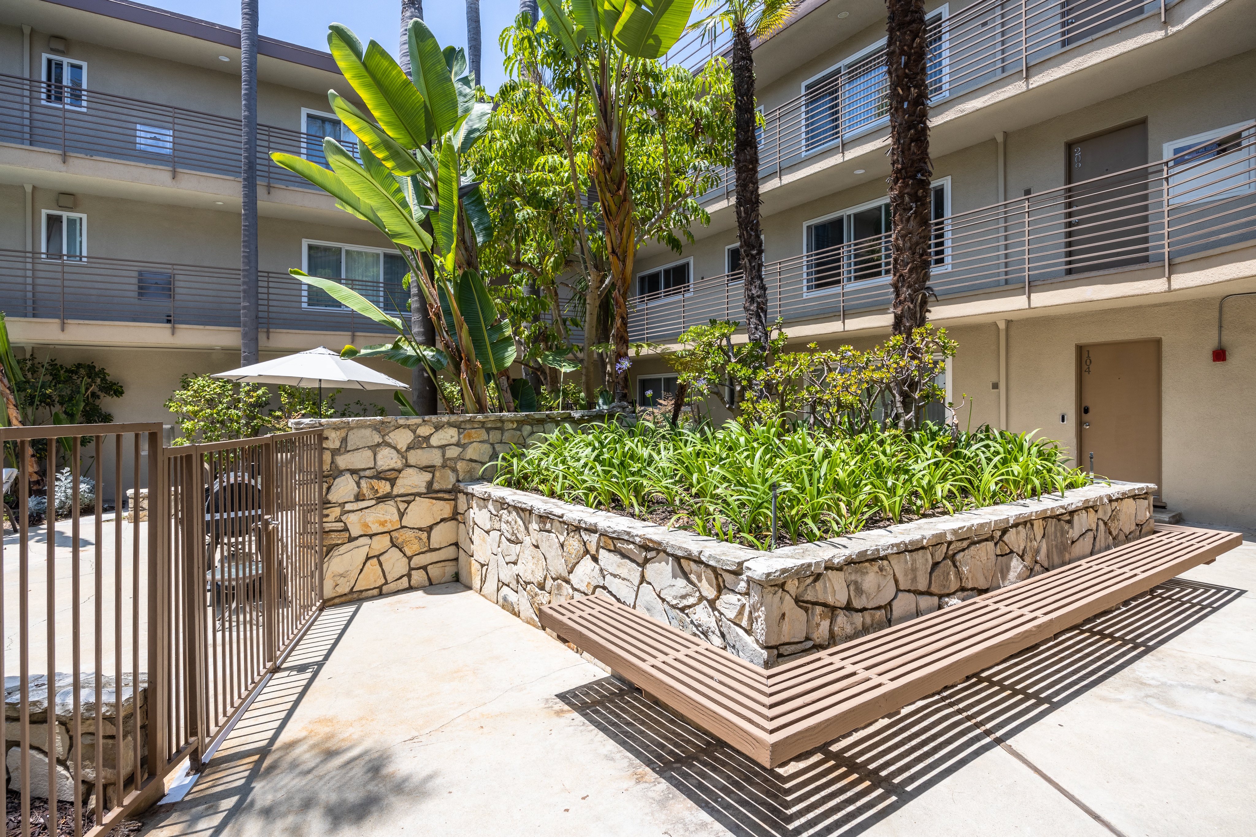a stone retaining wall with a wooden bench in front of an apartment building